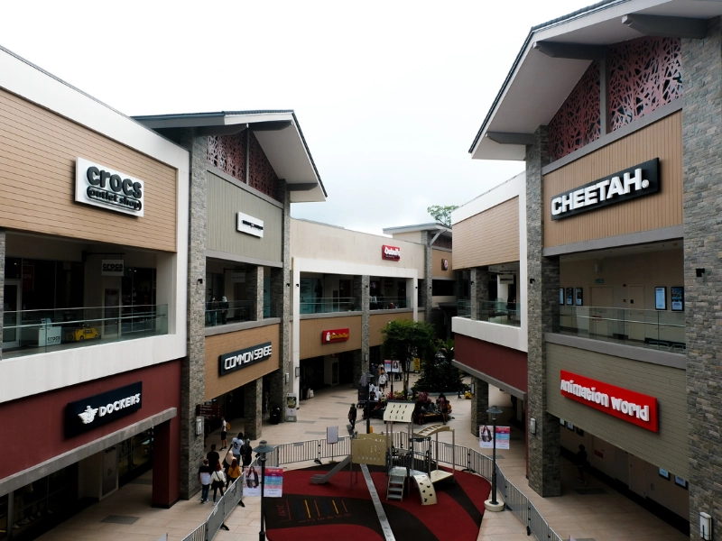 Various popular brand storefronts and shoppers at Genting Highlands Premium Outlets, a massive shopping haven you can visit stress-free with your Genting Highlands day trip private car.