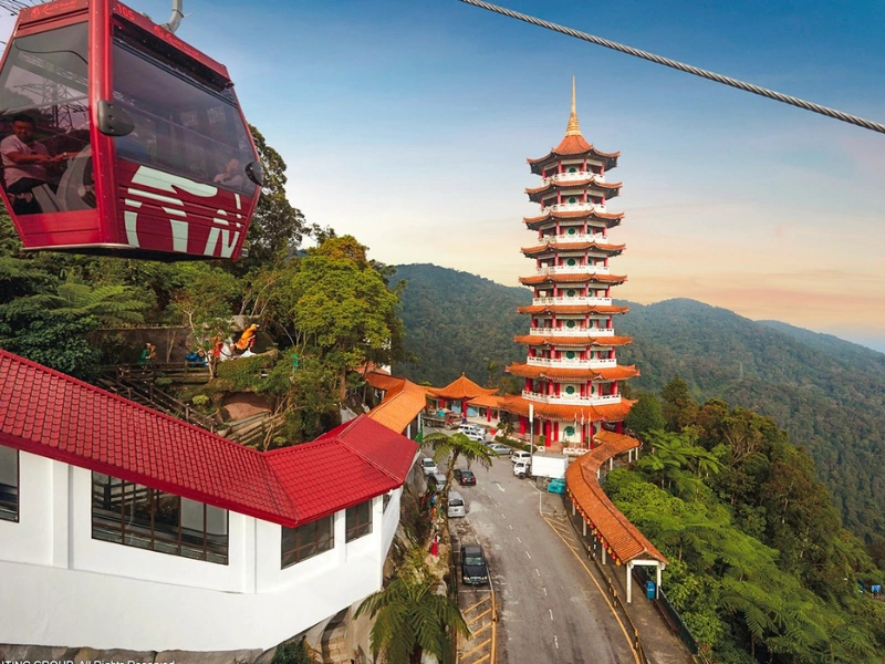 Red Awana SkyWay cable cars passing the Chin Swee Temple pagoda amidst lush rainforests, a scenic experience made hassle-free with your Genting Highlands day trip private car luggage transfer.
