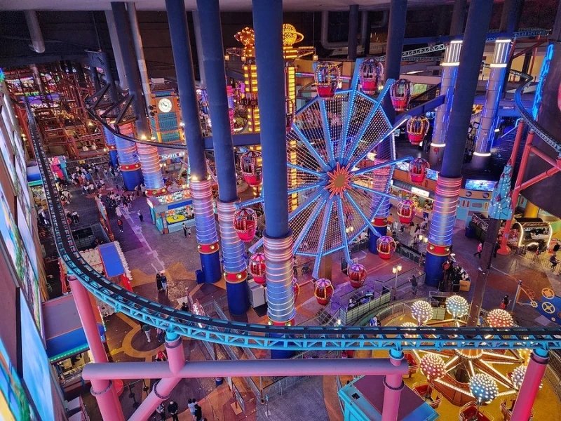 The colorful indoor Ferris wheel overlooking Skytropolis Theme Park, a magical attraction to enjoy before resting your tired legs in your Genting Highlands day trip private car.