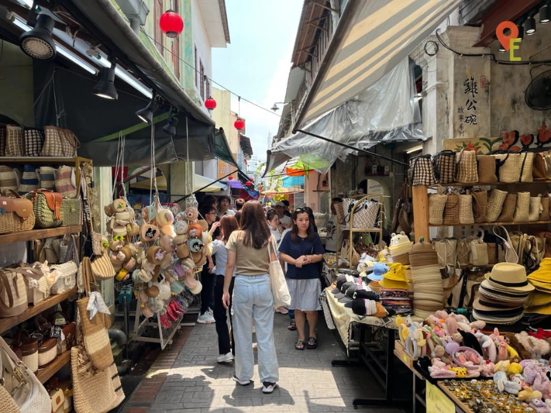 Tourists browsing vibrant souvenir stalls at Concubine Lane, a bustling market you can enjoy with hands-free shopping convenience on your Ipoh day trip.
