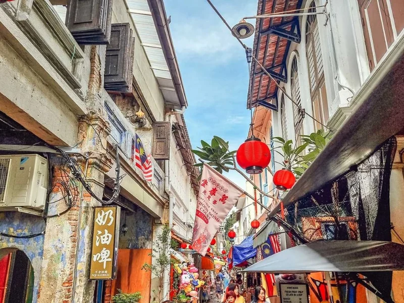 The bustling heritage street of Concubine Lane featuring red lanterns and local snacks, a vibrant cultural spot you can explore with convenient drop-offs on your Ipoh day trip.