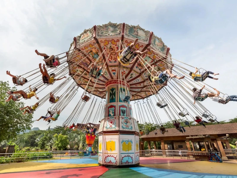 Families enjoying the wave swinger ride at the Lost World of Tambun amusement park, a joyful experience easily followed by a relaxing ride home on your Ipoh day trip.