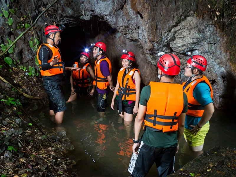 Tourists enjoying a wet cave exploration at Lost World of Tambun, a thrilling adventure perfectly followed by a restful ride in our private car on your Ipoh day trip.