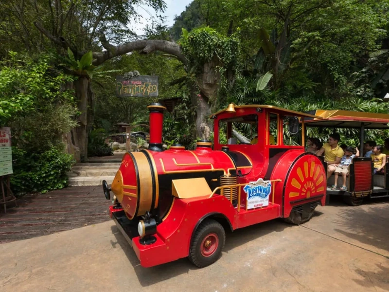 Families riding the red train near the petting zoo at Lost World of Tambun, a relaxing park experience easily followed by a comfortable ride home on your Ipoh day trip.