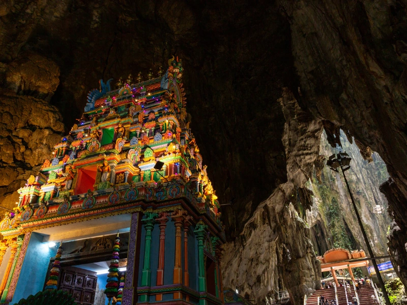 A colourful Hindu temple nestled inside the ancient limestone caverns of Batu Caves, a breathtaking highlight to include in your Kuala Lumpur day trip private car itinerary.