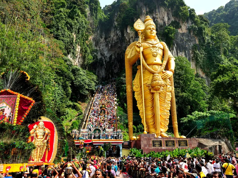 The massive golden Lord Murugan statue at the entrance to Batu Caves, a must-visit Hindu shrine on your Kuala Lumpur day trip private car itinerary.