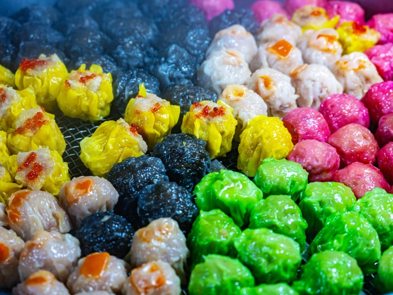 Steaming colorful dim sum and siew mai at Jalan Alor, a delightful street food snack to savor during your Kuala Lumpur day trip private car tour.