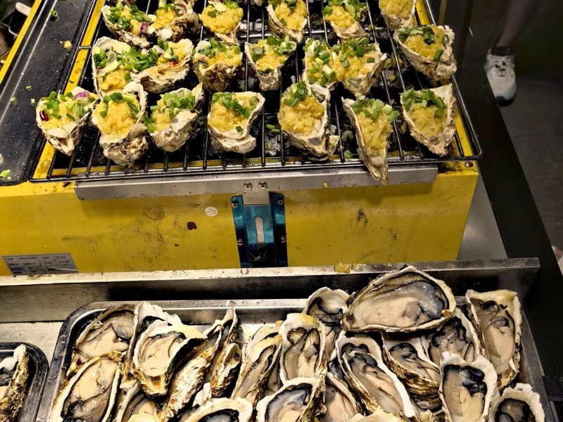 Mouth-watering garlic grilled oysters at Jalan Alor night market, a must-try seafood delicacy easily enjoyed on your Kuala Lumpur day trip private car tour.