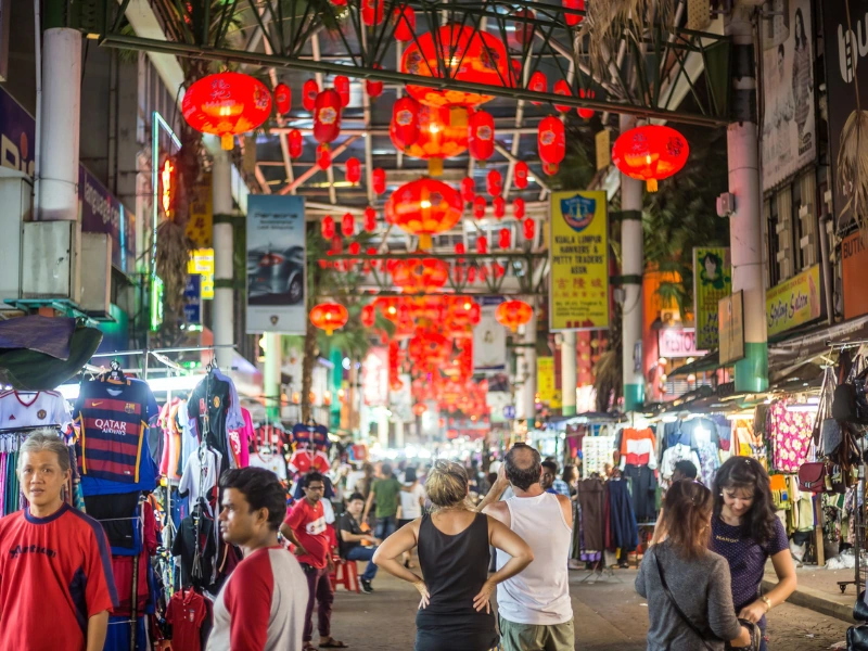 Red lanterns illuminating the bustling night market stalls at Petaling Street, a vibrant cultural experience made effortless with your Kuala Lumpur day trip private car.