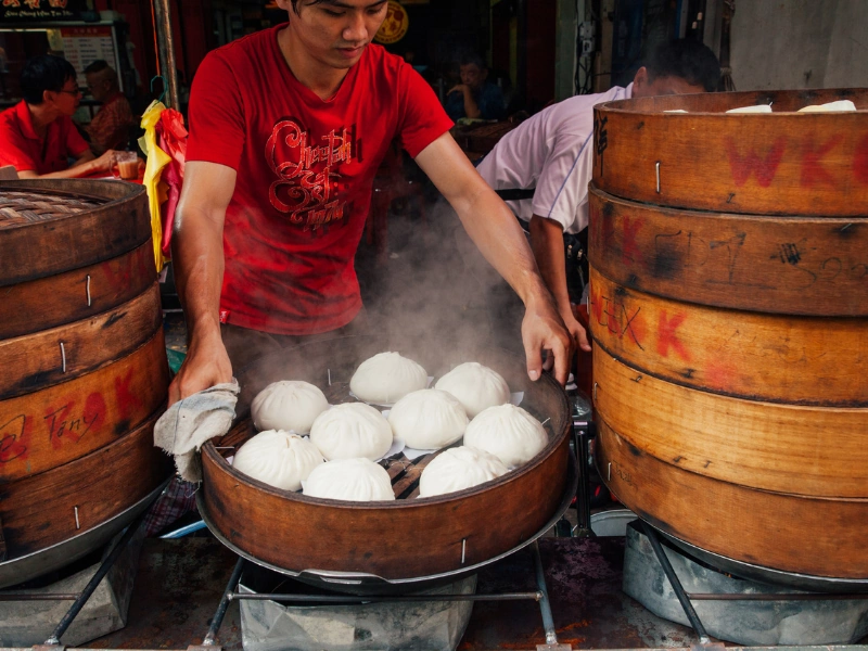 Hot, freshly steamed traditional buns in wooden steamers at Petaling Street, an authentic street food tasting experience on your Kuala Lumpur day trip private car tour.