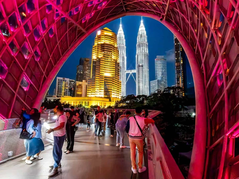 The iconic Petronas Twin Towers beautifully framed by the illuminated Saloma Link bridge at night, a picture-perfect stop to enjoy comfortably on your Kuala Lumpur day trip private car tour.