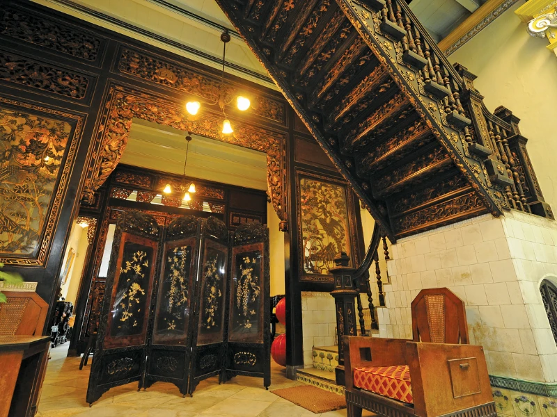 Intricate wooden interior and antique furniture of the Baba & Nyonya Heritage Museum, a fascinating cultural discovery during your Malacca day trip private car tour.