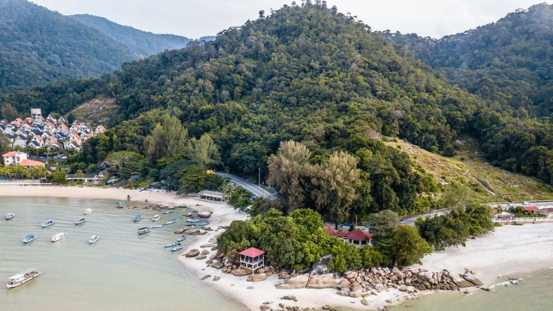 The beautiful coastline and white sands of Batu Ferringhi beach, a relaxing tropical escape you can reach comfortably without driving stress on your Penang Day Trip private car.