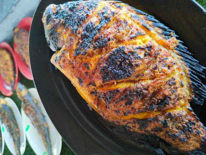 Signature charcoal-grilled fish topped with sambal at Abah Ikan Bakar, a mouth-watering Halal delicacy highly recommended by experienced drivers on your Sekinchan day trip private car tour.