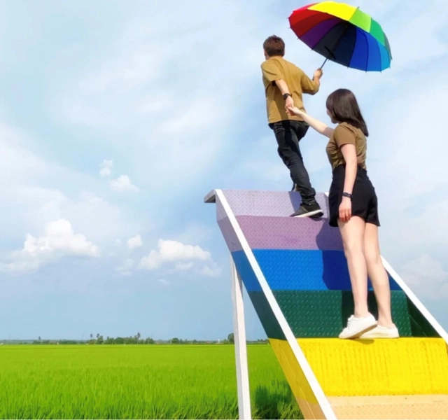 A couple posing on the iconic Rainbow Stairway to the Sky in the middle of Sekinchan paddy fields, a trendy Instagrammable spot visited during your flexible Sekinchan day trip private car tour.