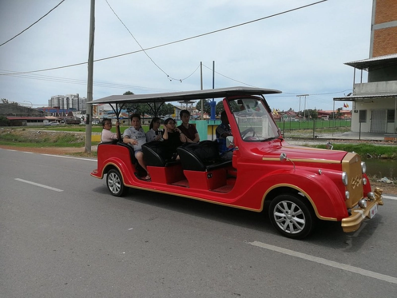 Tourists enjoying a fun ride on the iconic red vintage sightseeing car in Sekinchan, a local experience you can easily try with our flexible Sekinchan day trip private car service.