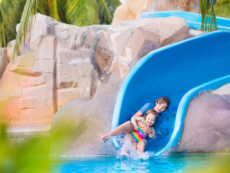 Two happy kids playing on a water slide at Tioman Island, the perfect family getaway easily reached via our Singapore to Mersing day trip transfer.
